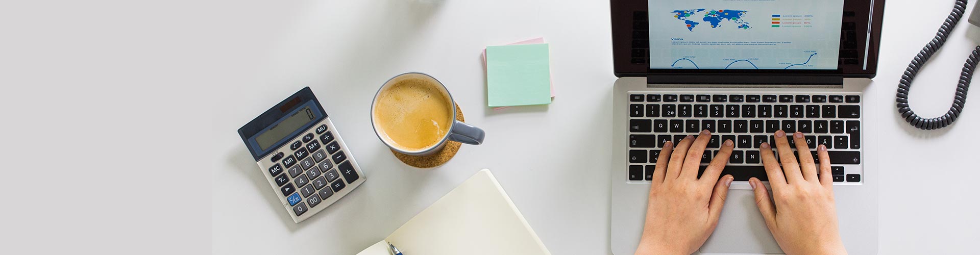 Operaciones en divisas - Mesa de despacho con una calculadora, una taza de café, un bloc de notas, un teléfono y un portátil Operaciones en divisas - Mesa de despacho con una calculadora, una taza de café, un bloc de notas, un teléfono y un portátil