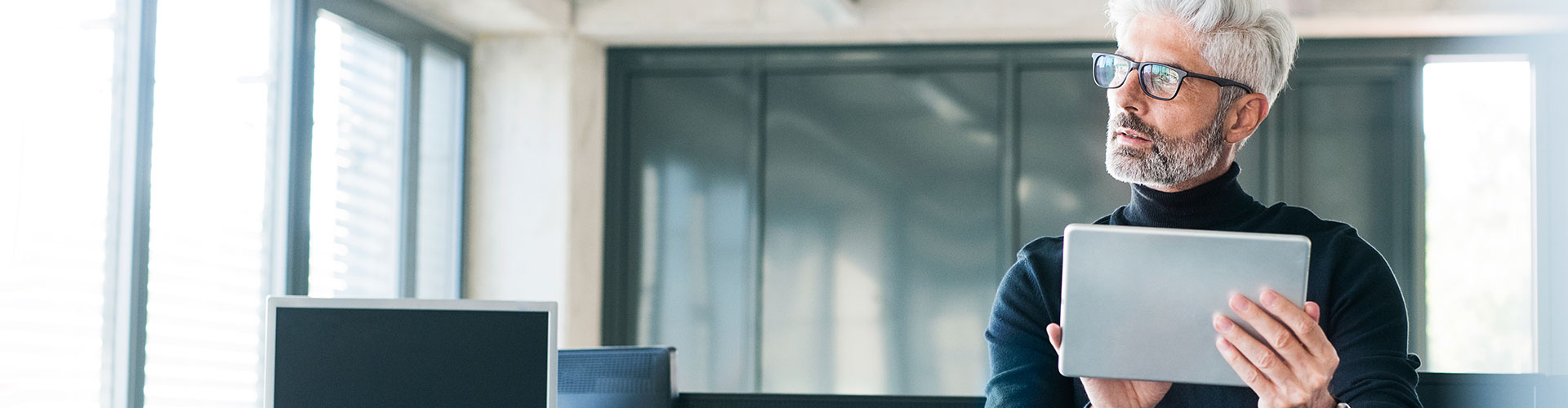 Bolsa y Mercados Empresas - Hombre de negocios de mediana edad con gafas y una tablet en las manos en la oficina Bolsa y Mercados Empresas - Hombre de negocios de mediana edad con gafas y una tablet en las manos en la oficina