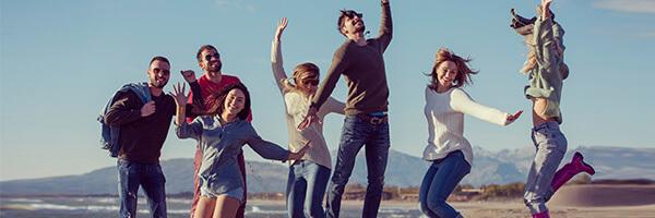 Programa Jovenes - Chicos jovenes saltando juntos en la playa